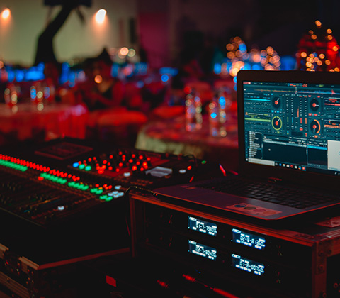 A laptop on a table with a sound board and lights