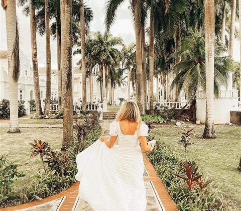 Woman running along a paved path with palm trees