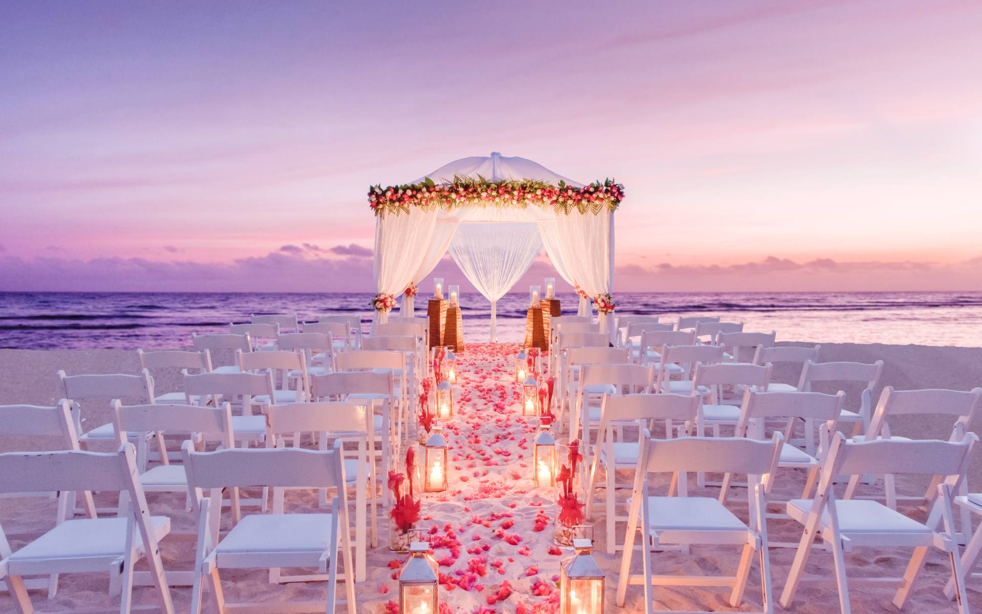 Outside wedding on the beach facing the ocean with soft light lanterns