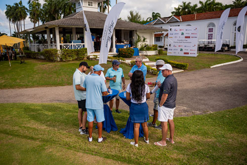 A small group of people gathered around two bar tables chatting