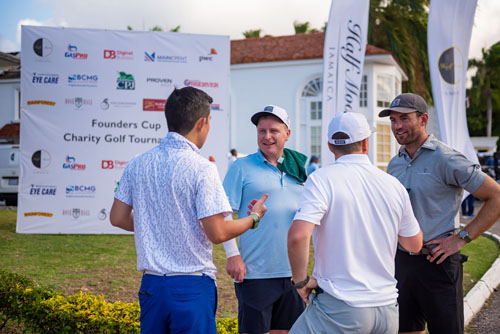 Guys chatting together in front of the Founders Cup Charity Golf Tournament Sign