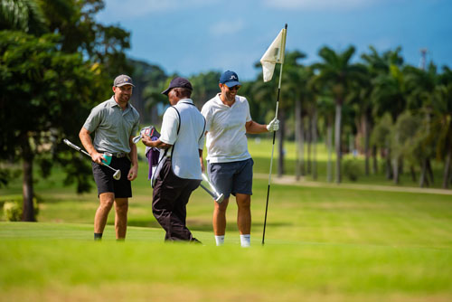 Guys smiling with each other while moving the flagstick