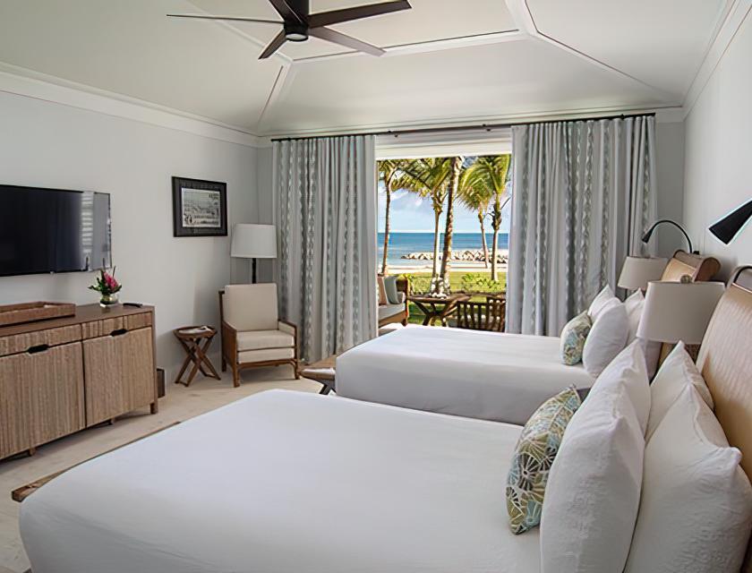 A room with two beds and a window with a view of the ocean