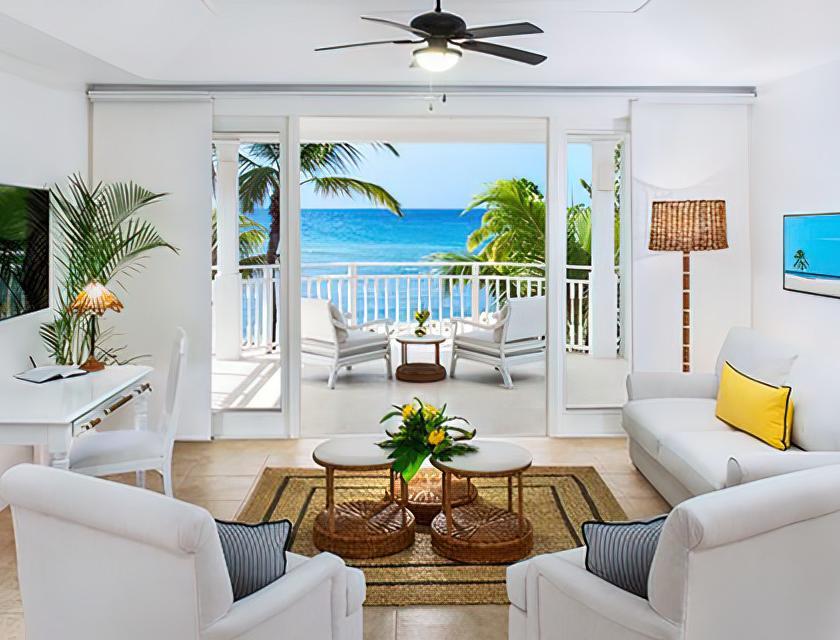 A living room with white furniture and a view of the ocean