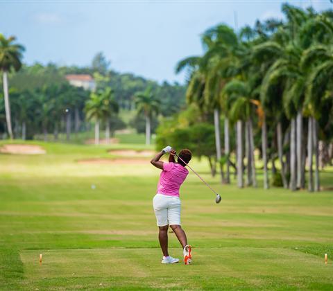 A woman swinging a golf club on a golf course