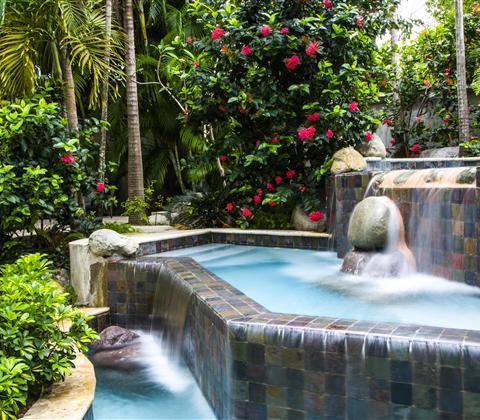 A pool with a waterfall and a rock in the middle