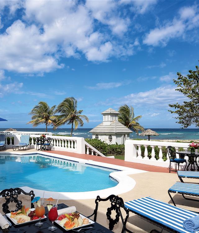A pool with a table and chairs and a beach house